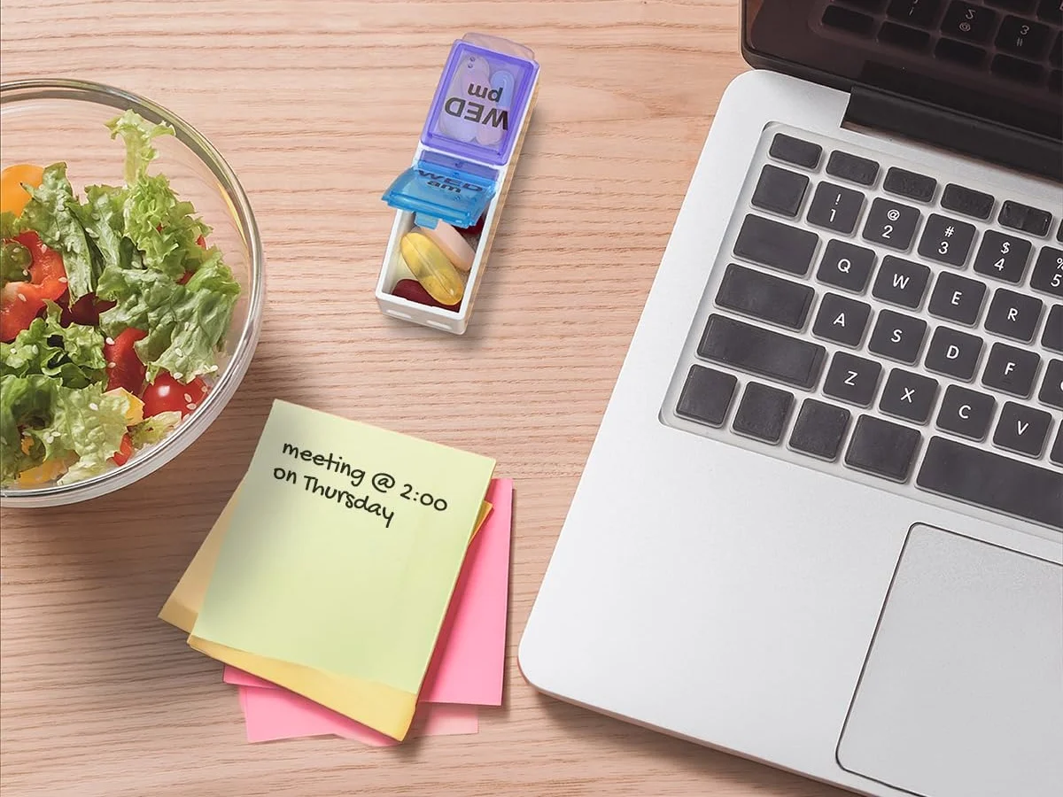 A single day out of the pop-out tray, beside a laptop and a salad